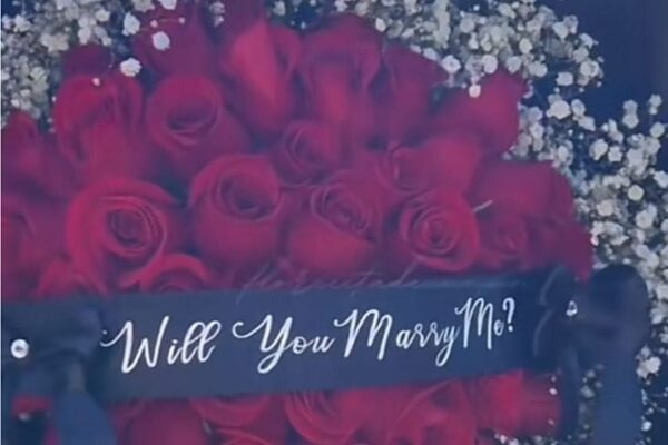 Demande en mariage. Gros plan : bouquet de fleurs avec un bandeau "Will You Marry Me?"